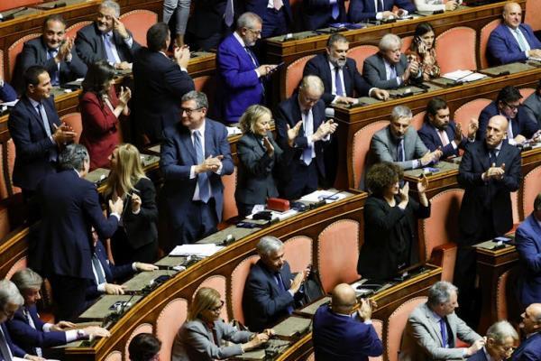 Members of the Italian Senate standing in the chamber clapping.